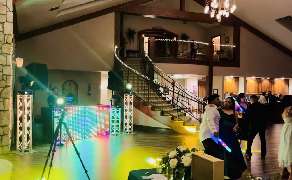 Pista de baile en salón con escalera iluminada e invitados
